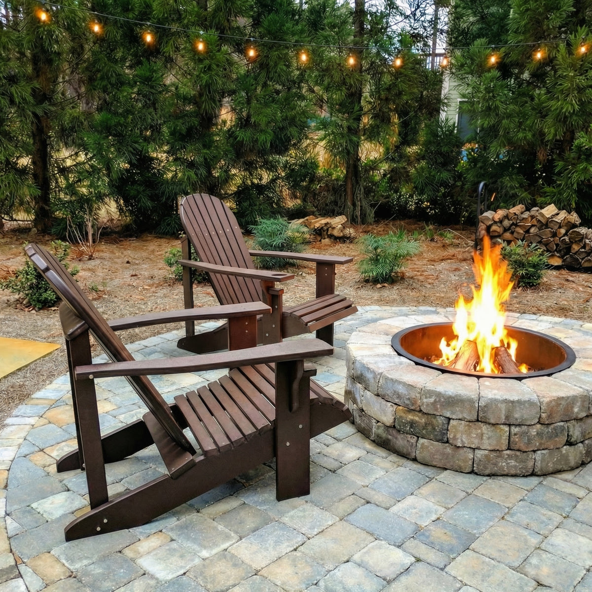 Two wooden Adirondack chairs around a fire pit with string lights in the background.