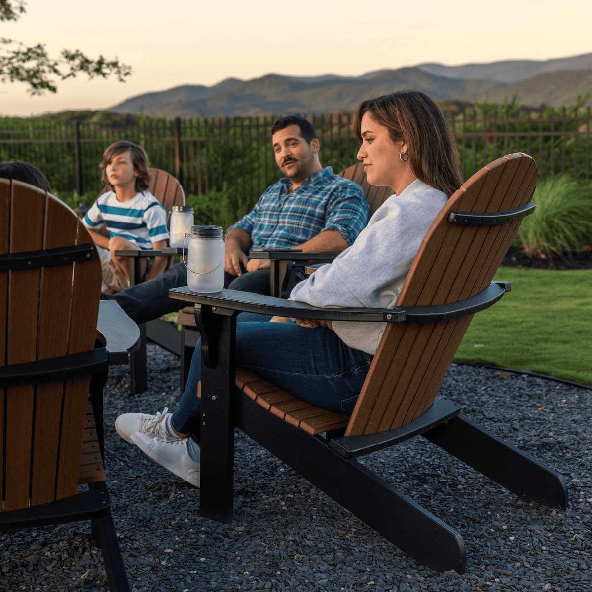 Family sitting outdoors in Adirondack chairs with a scenic background