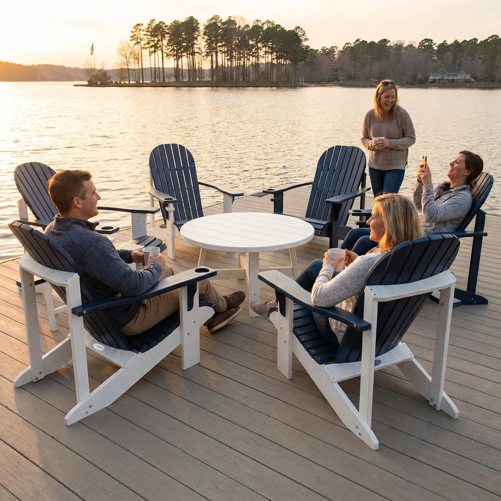 People sitting around a table on a dock by a lake at sunset