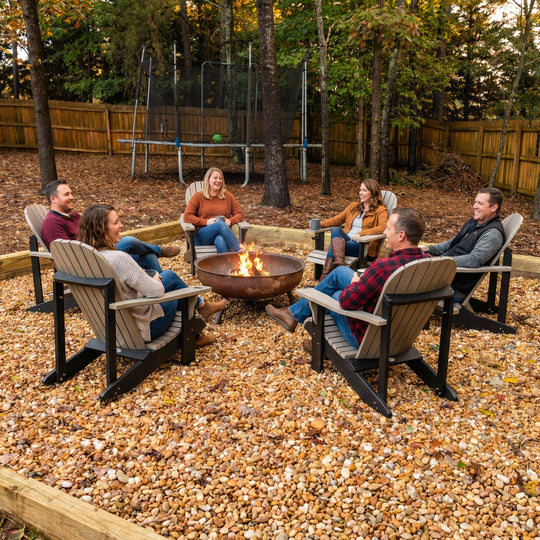 Group of people sitting around a fire pit in a backyard setting.