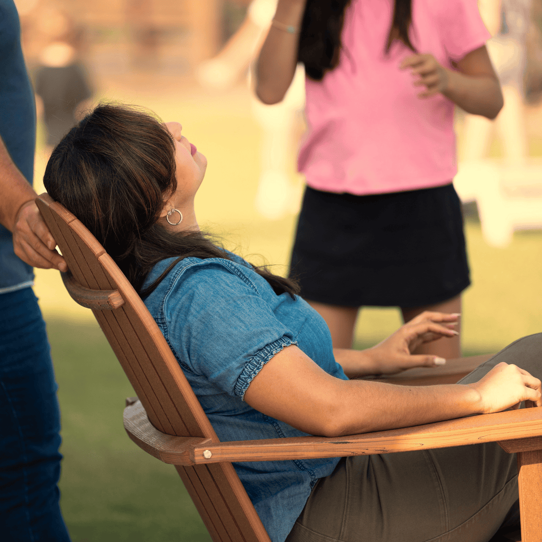 Woman sitting in a wooden chair outdoors with people in the background