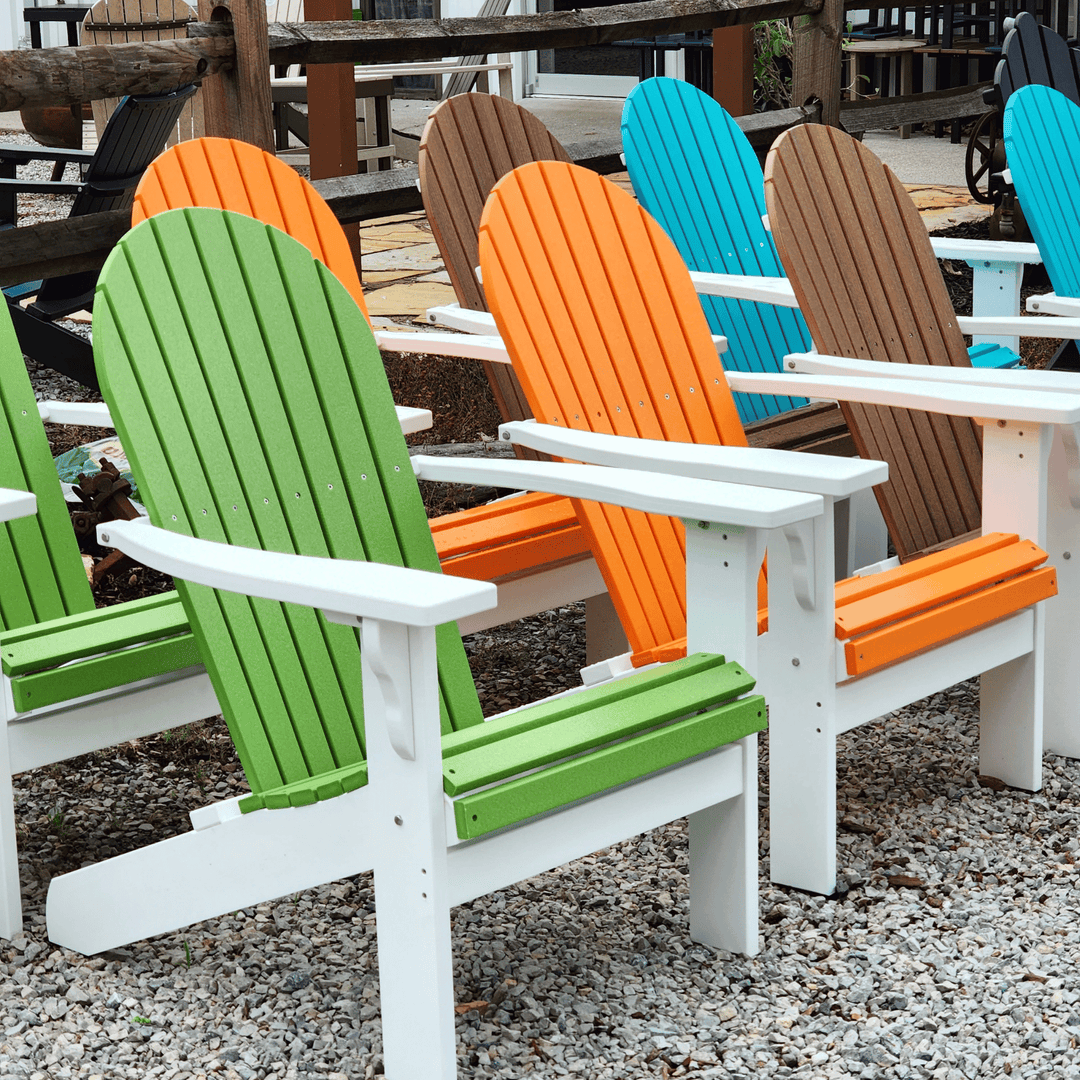 Colorful Adirondack chairs on a gravel surface with wooden tables in the background.