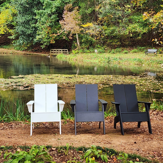 Outdoor furniture set by a pond with trees in the background
