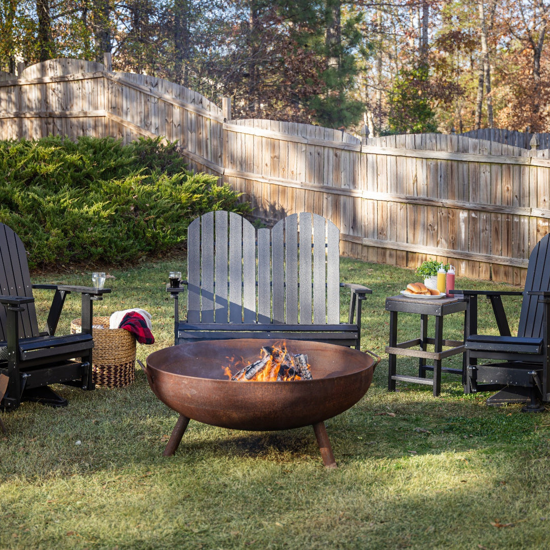 Outdoor setting with Adirondack chairs around a fire pit in a backyard.